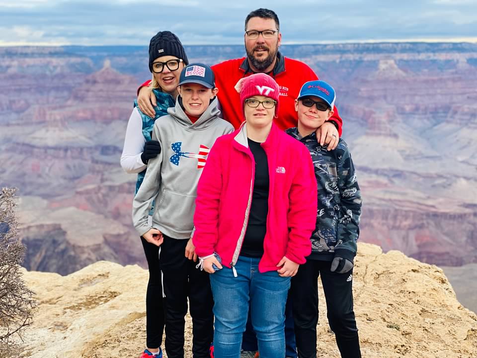 Shannon with her three kids and her husband on the top of a mountain a the end of a hike.