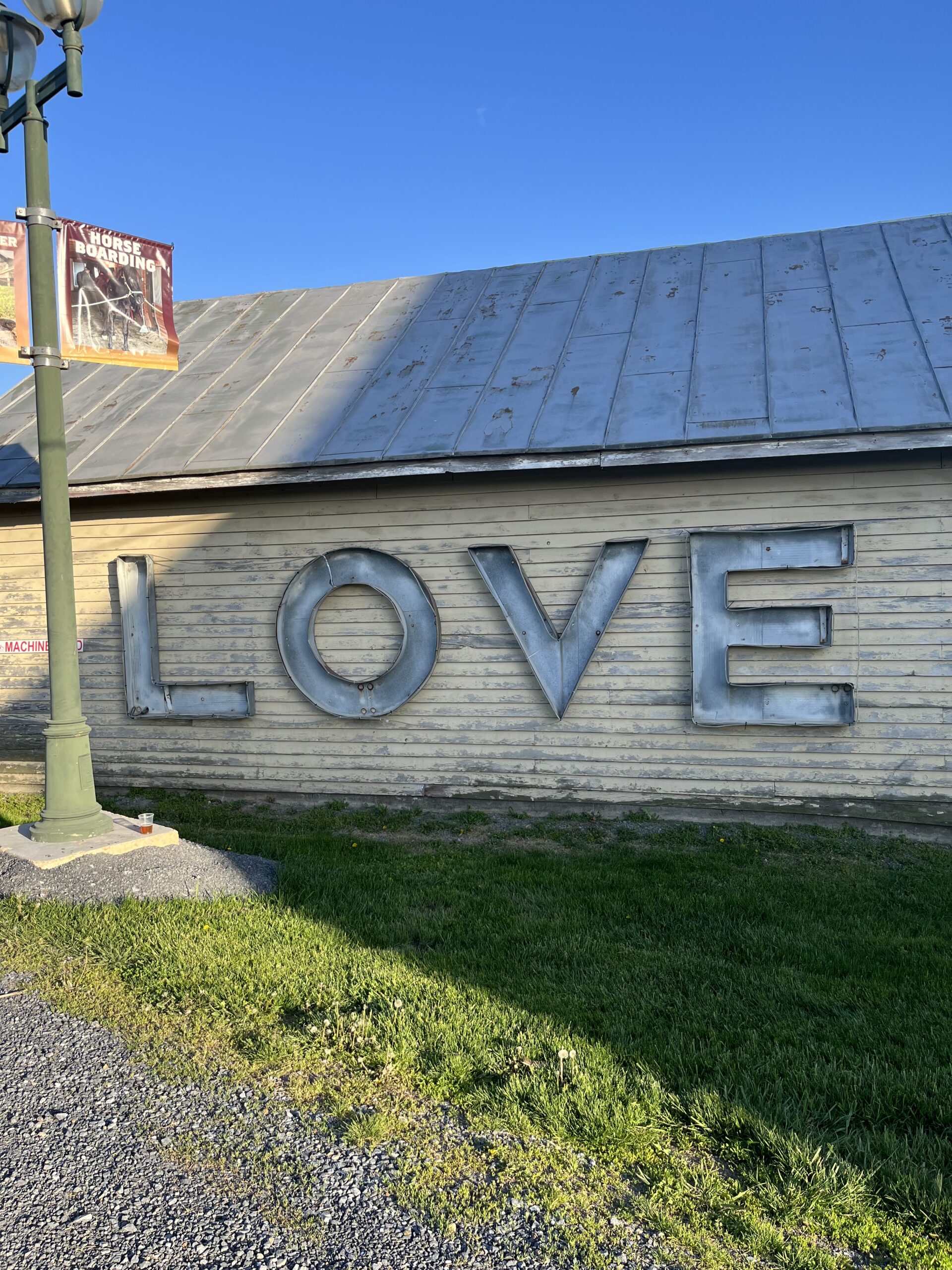 An old yellow shack with metal letters on the side of it that spell out love