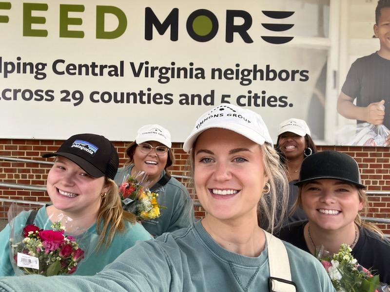 Timmons Group's HR team posing outside of the Feed More building for a selfie while holidng flower bouquets.