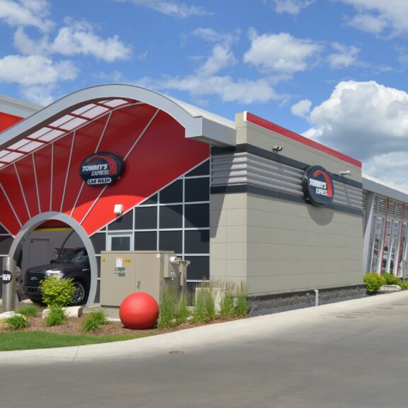 A red and black car wash featuring a prominent red and white roof against a clear sky.