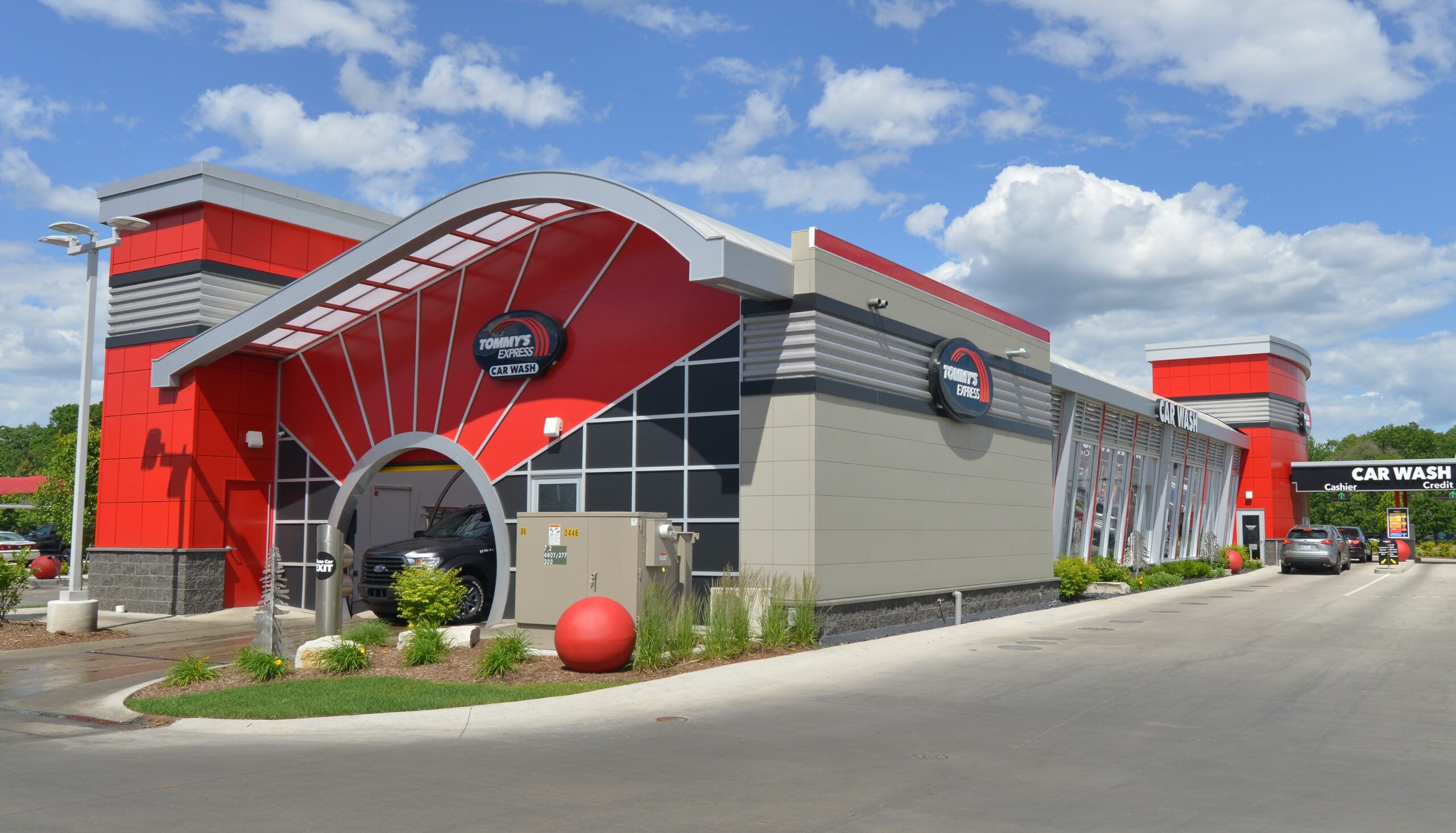 A red and black car wash featuring a prominent red and white roof against a clear sky.