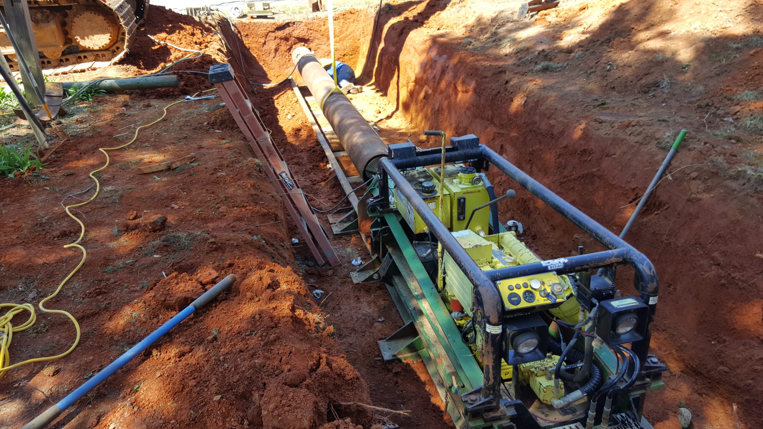 A construction machine operates in a dirt trench, digging and moving soil for excavation purposes.