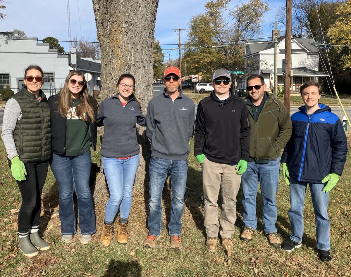 Photo of seven Greensboro employees standing together outside and wearing bright green gloves.