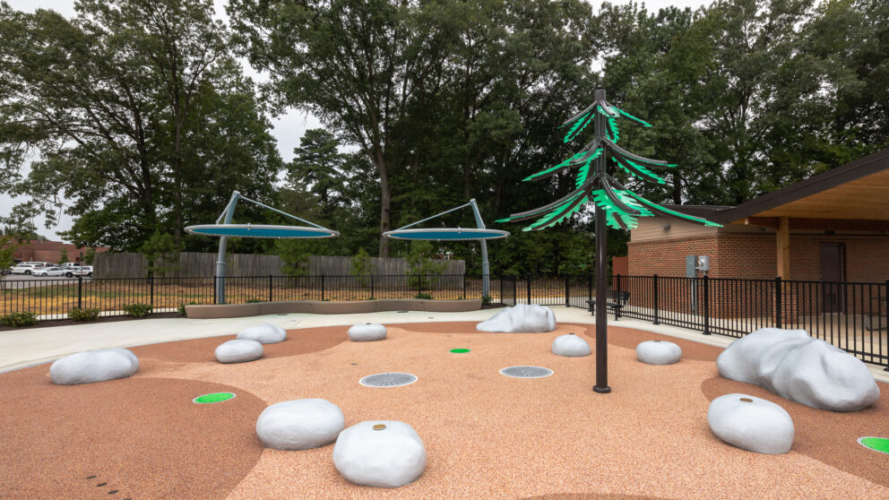 A water play area in the shape of rocks in dirt at the Beluah Park playground.