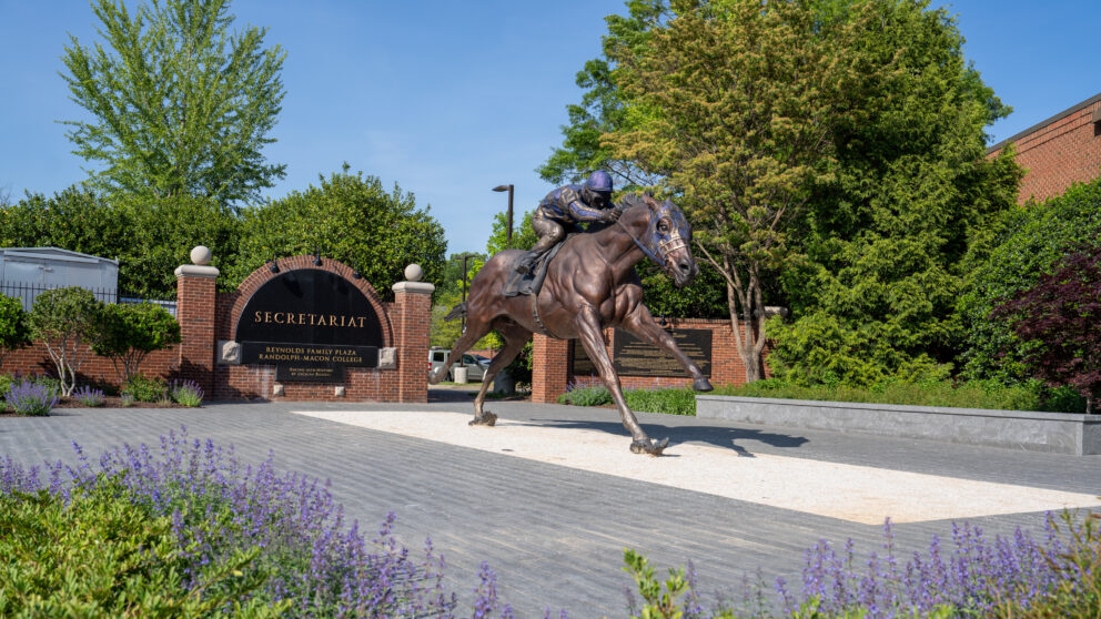 A large statue of a man riding a horse outside a gate.
