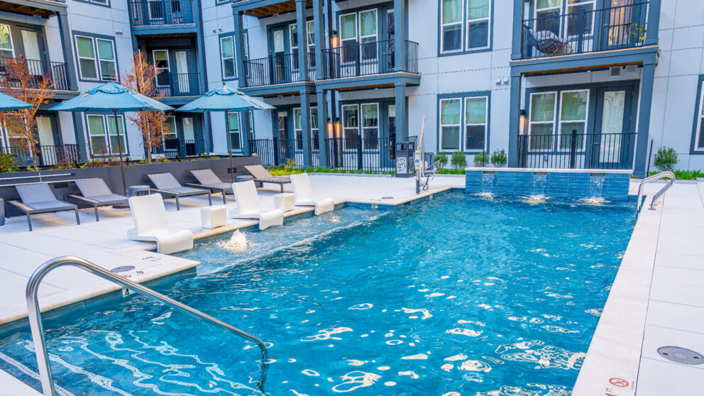 The bright blue pool which is surrounded by the apartment walls