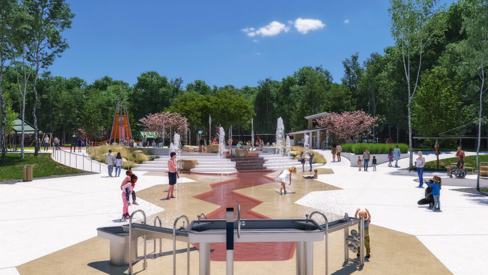 A side view of children playing in the water-playground. Water fountains are in the foreground.