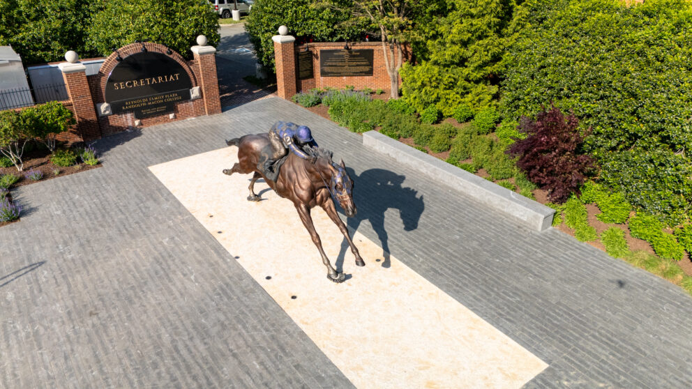 A large statue of a man riding a horse outside a gate.