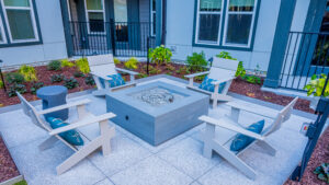 A sitting area with four lawn chairs circling a firepit. A mulch bed and the apartment walls surround the platform.