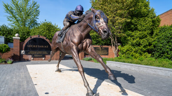 A large statue of a man riding a horse outside a gate.