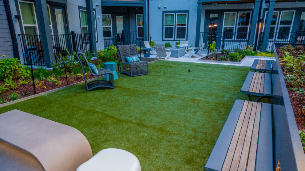 A lawn outside the apartment with three benches and two chairs.