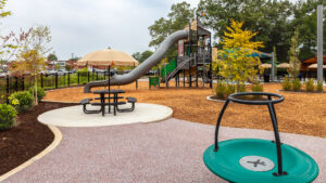 A table and umbrella and play equipment at the playground at Beulah Park.