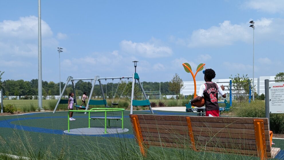 A bench facing the playground with children playing at the TB Smith Community Center.
